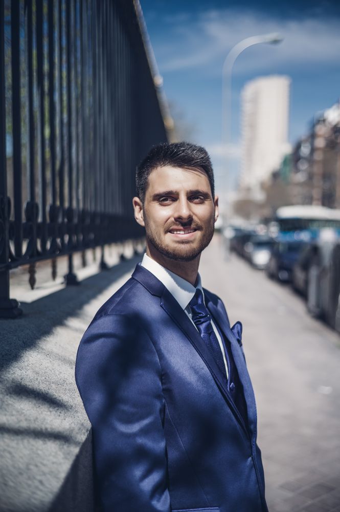 Smiling young groom near fence on street