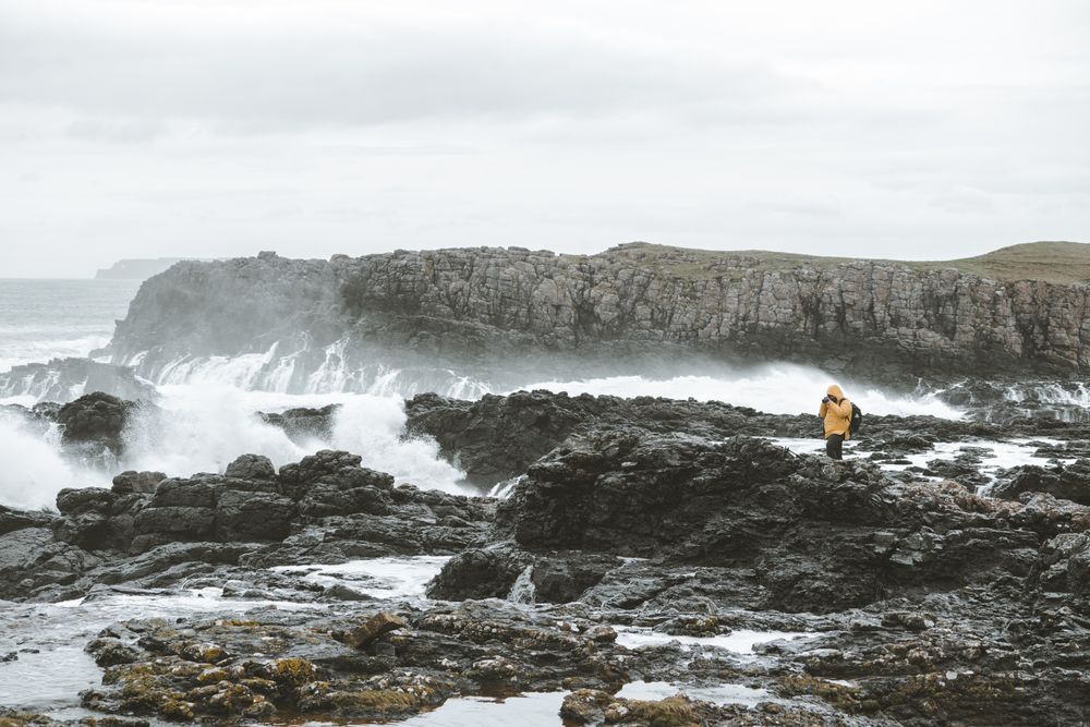 Man standing on rock and taking picture of sea