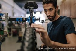 Man with beard concentrating on fixing a bicycle wheel 436jg5
