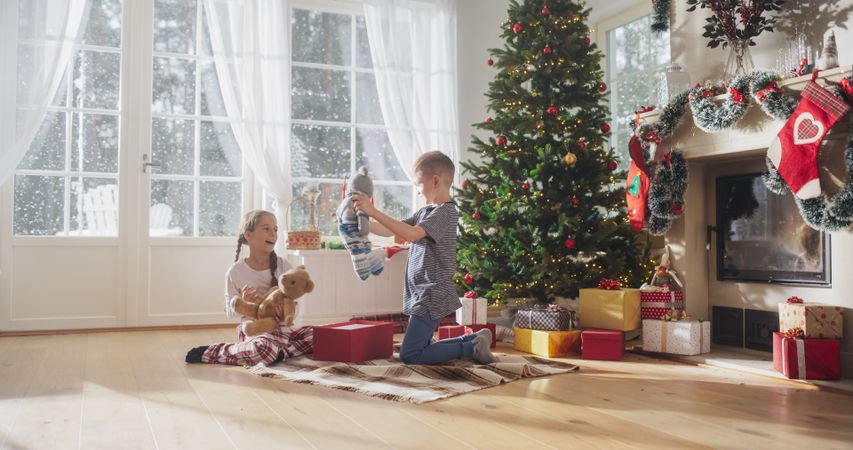 Happy Kids Getting Surprised While Opening Holiday Wrapped Gift Boxes, Receiving New Toys from Santa
