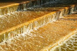 Artificial stair-stepping waterfall in sunny morning