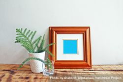 Square wooden picture frame on wooden desk with branches mockup 49dD65