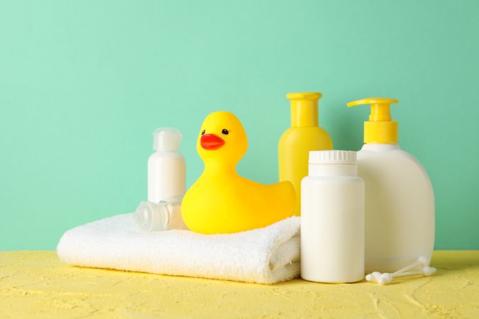 Baby hygiene accessories on yellow table against mint background