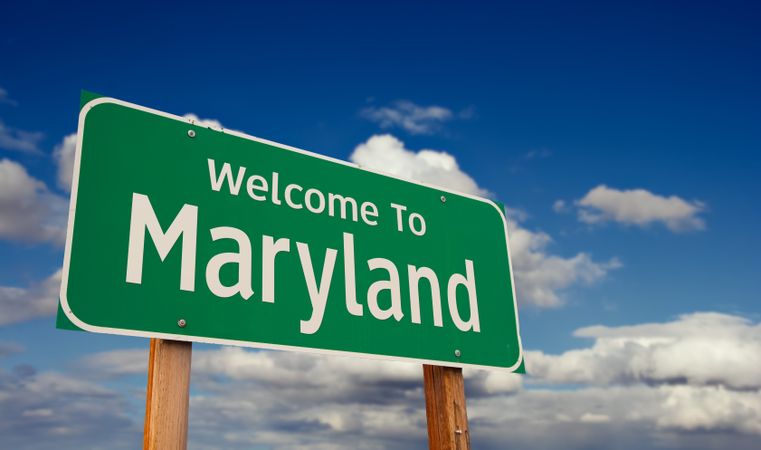 Welcome To Maryland Green Road Sign Over Blue Sky with Some Clouds.