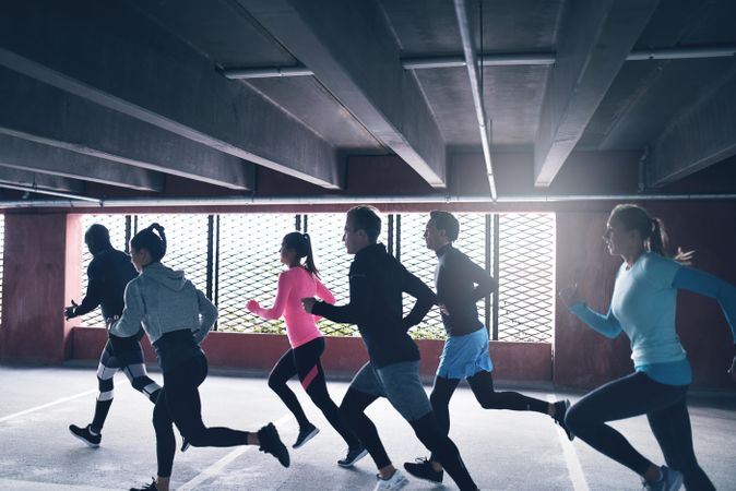 Group of sporty people running together next to a barred window