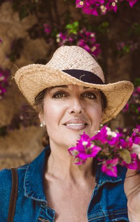 Woman standing near a wall with flower shrubs