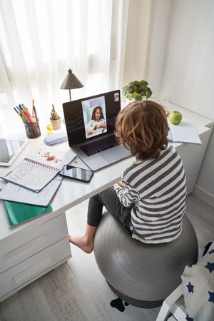 Anonymous boy video chatting with classmate during schoolwork