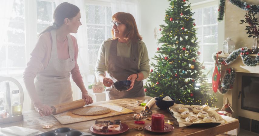 Portrait of Adult Woman Preparing Gingerbread for Christmas While her Older Mother is Helping.