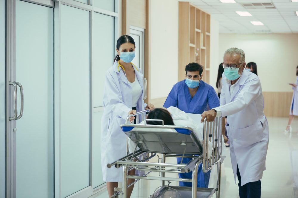 Medical staff wheeling patient in bed through hospital