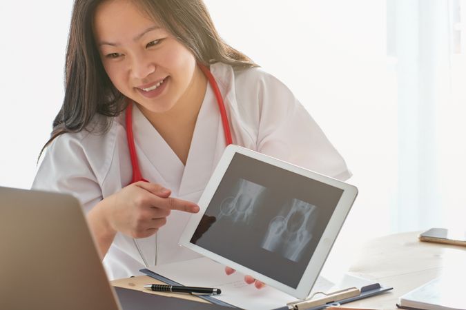 Positive Asian medic showing x ray during video call