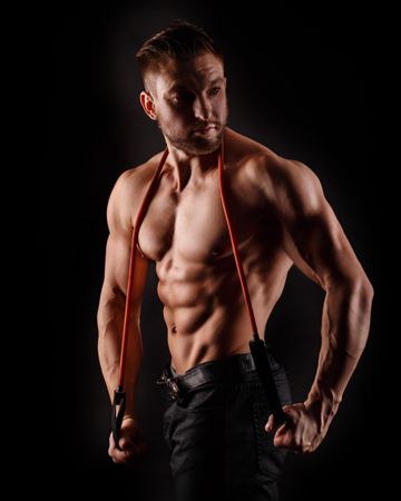Bodybuilder practicing upper body poses ahead of competition in dark studio