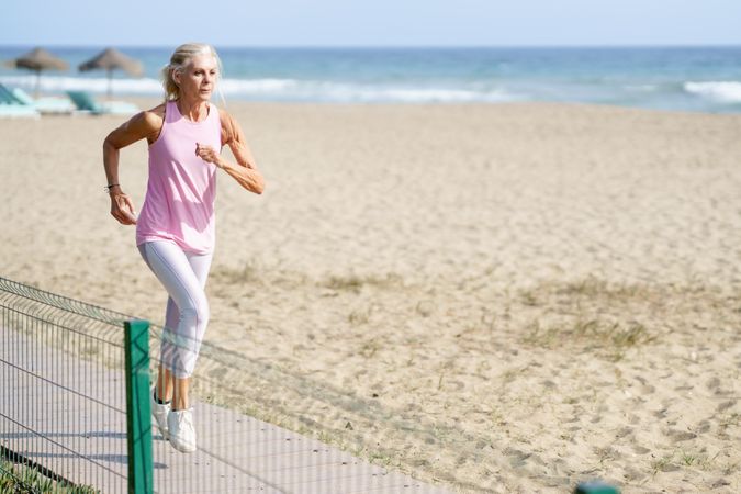 Older woman in sports gear running along beach