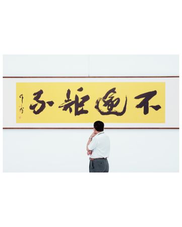 Man in light dress shirt and standing beside kanji text
