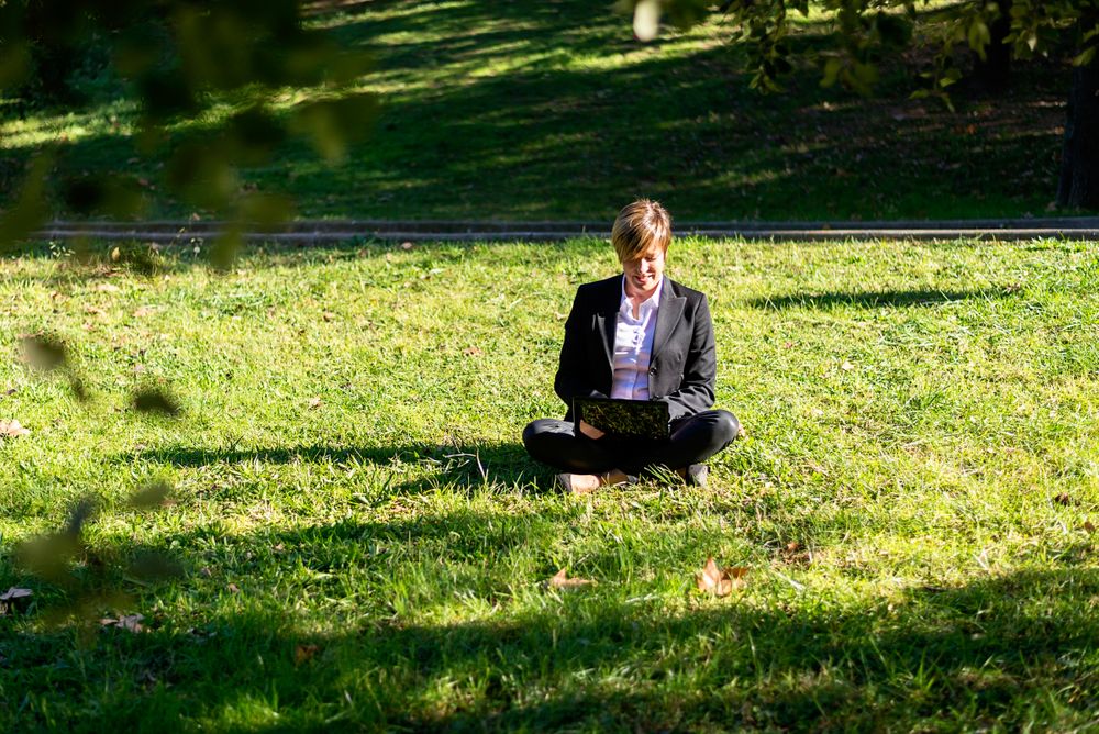 Woman sitting crosslegged on grass in park on sunny day