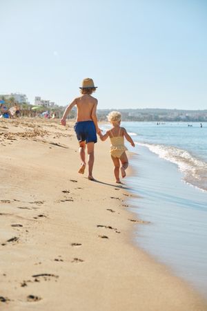 Children running on sandy beach in summer