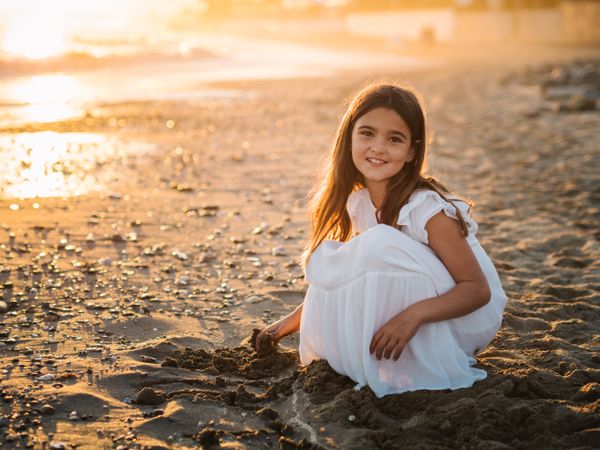 Adorable girl playing with sand on beach