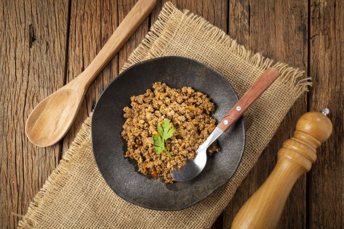 Ground beef in dark plate on the table.
