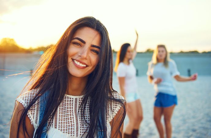 Portrait of brunette woman with friends in background on beach
