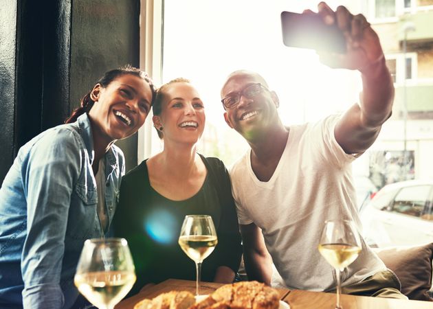 Three good friends taking a selfie over wine