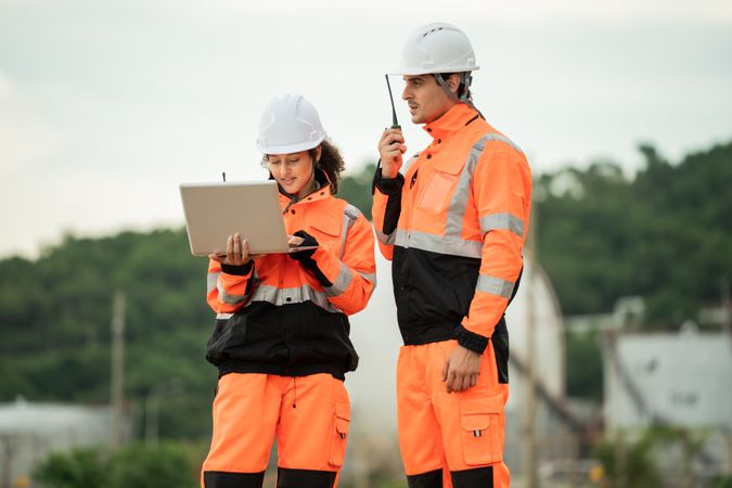 Two engineers are working at an industrial site near spherical gas storage tanks.
