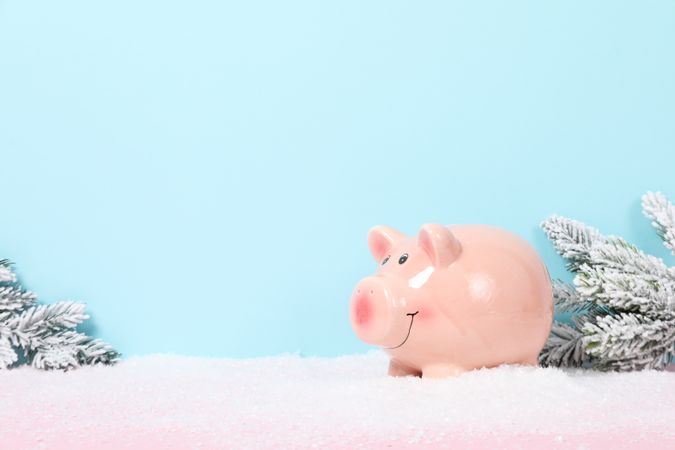 Piggy bank and snow on blue background, space for text
