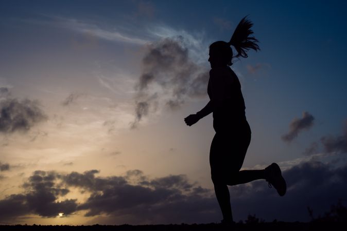 Jumping woman and sky with clouds at sunset