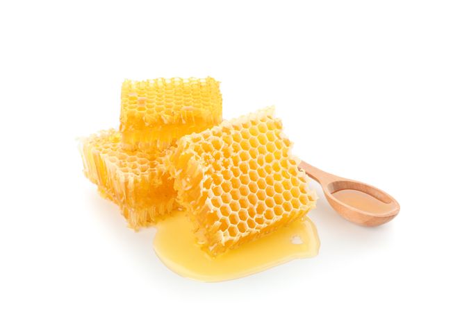 Pieces of honeycomb and wooden spoon isolated on blank background