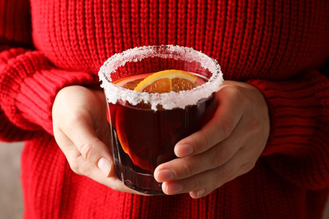 Girl in red sweater holding glass with mulled wine, close up