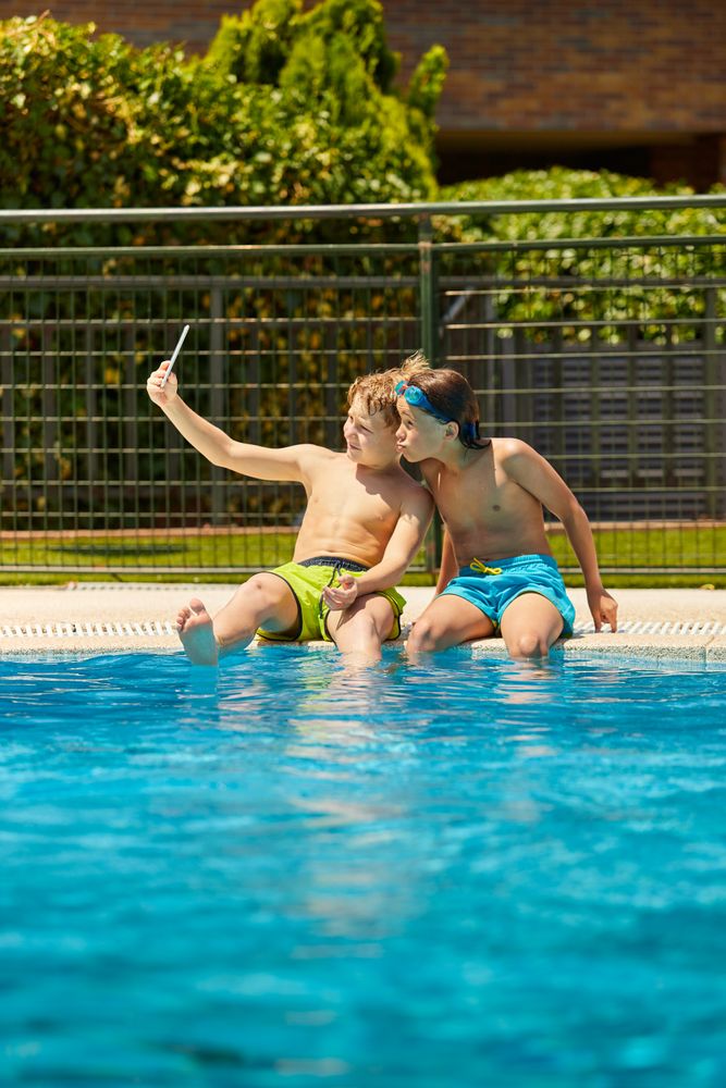 Boys on poolside taking selfie
