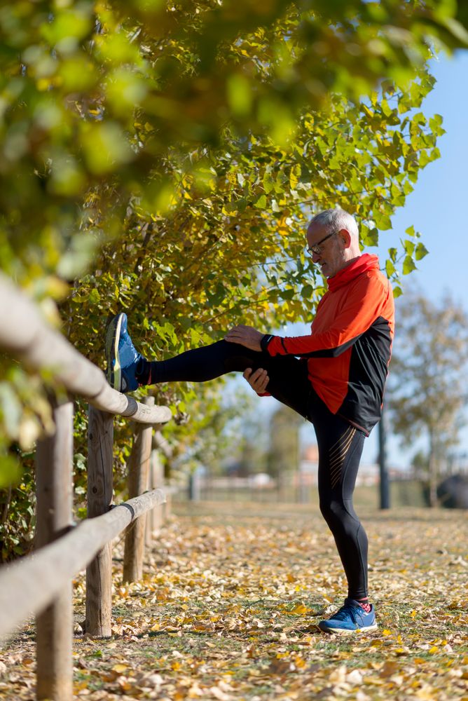 Vertical shot of male stretching legs on fence