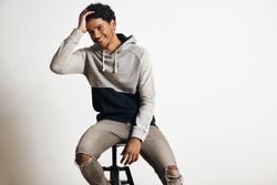 Man holding head while smiling and sitting on stool in studio shoot