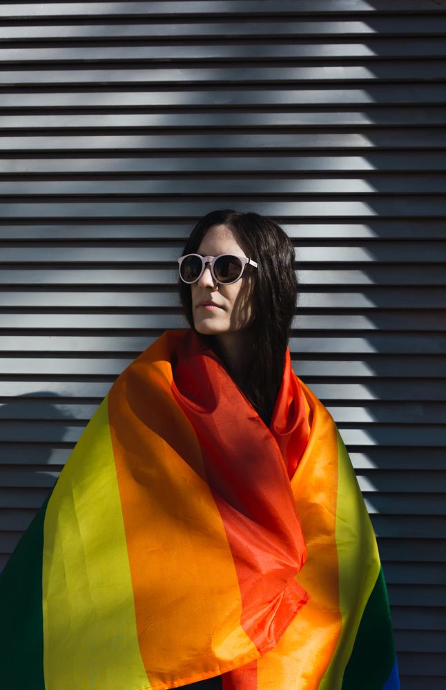 White Woman posing happily with the LGBTQ flag