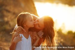 Woman leaning down giving her daughter a kiss at dusk 5rmdZ0