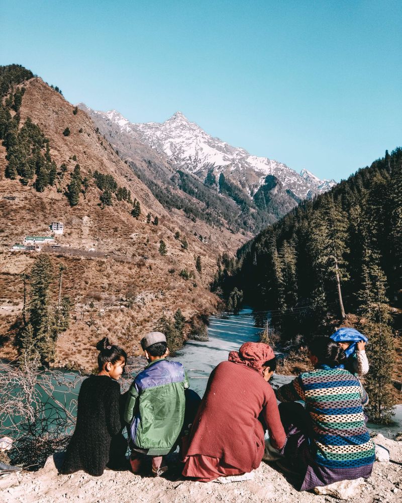 Back view of children and women sitting and looking at the mountainous landform in India