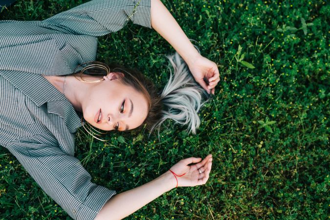 Woman in stylish suit lying in grass