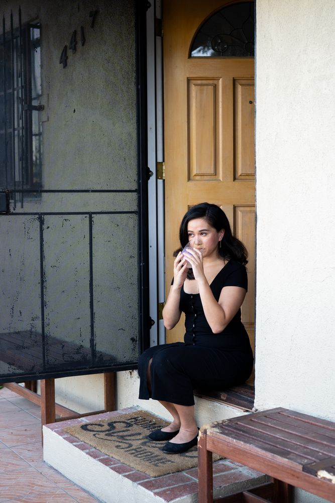 Woman sitting on her front steps drinking a glass of wine