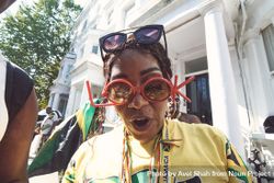 London, England, United Kingdom - August 25th, 2019: Woman in Jamaican attire with party glasses bxAKr0