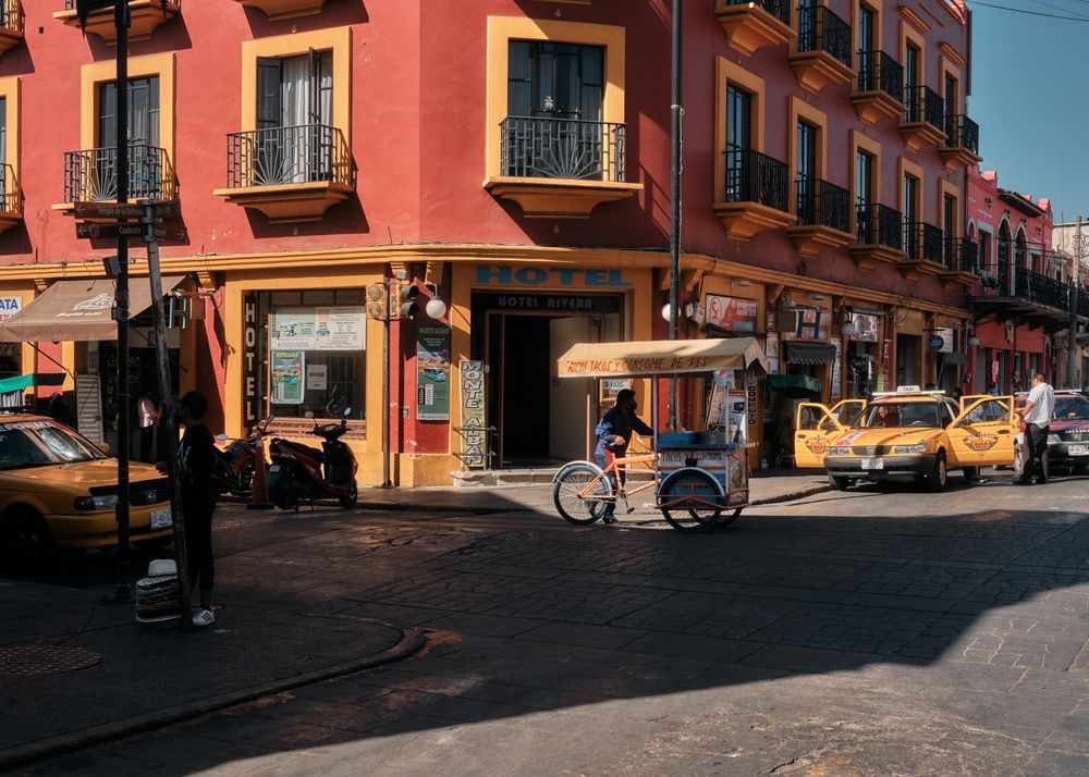 Man walking with food cart across street
