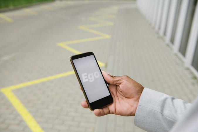 Person holding smartphone with text Ego on screen