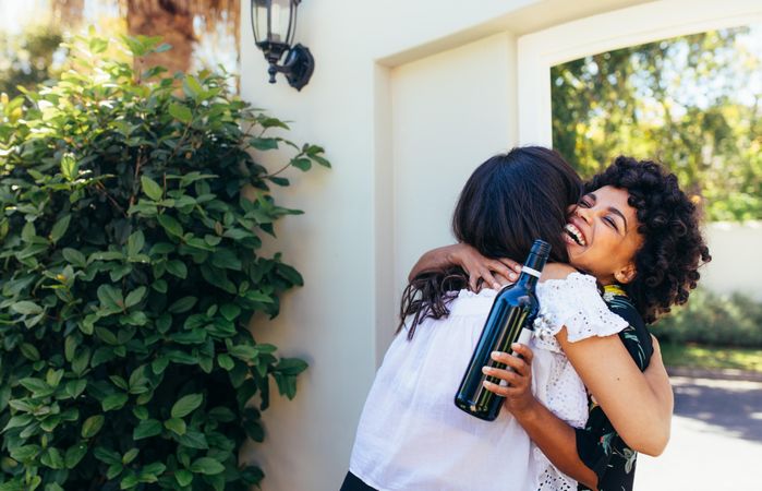 Black woman greeting and embracing female friend for having a new house