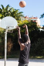 Anonymous Black man playing basketball on sports ground