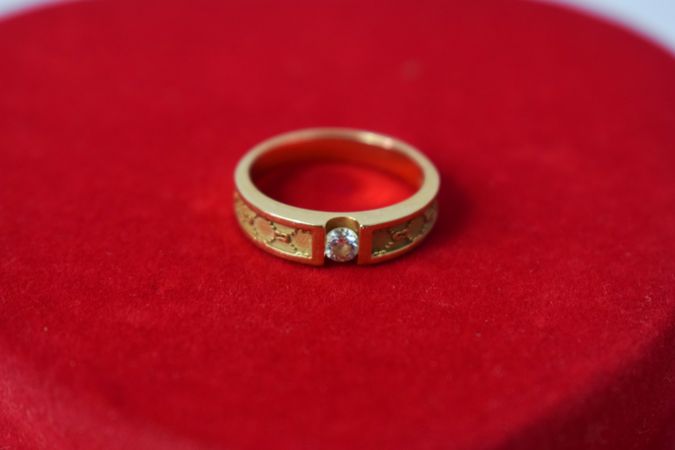 Man's diamond gold ring on red clothed table with copy space