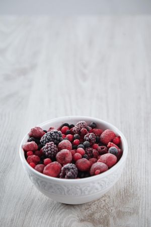 Ceramic bowl of frozen berries, vertical