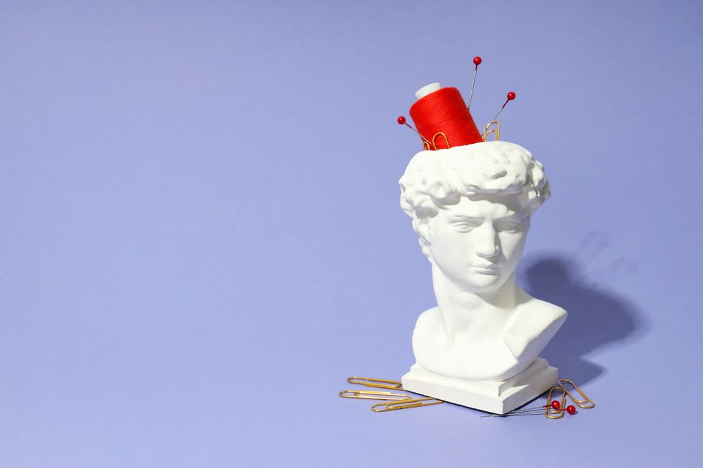Pins and red spool in bust in purple studio, copy space