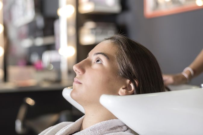 Female sitting with head back in sink at hairdressers awaiting a wash