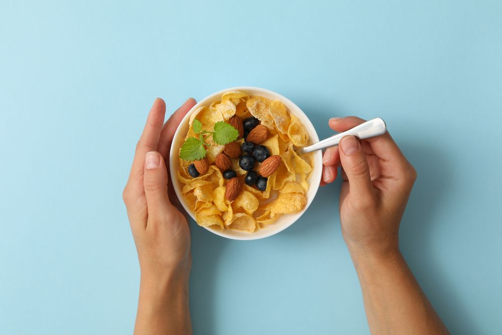 Female hands hold bowl of muesli on blue background