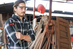 Male carpenter in woodshed holding a ruler