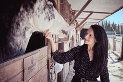 Woman stroking horse in stall