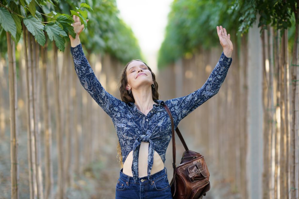 A Joyful Woman is Deeply Embracing Nature while Surrounded by a Lush Green Aisle of Life and Beauty