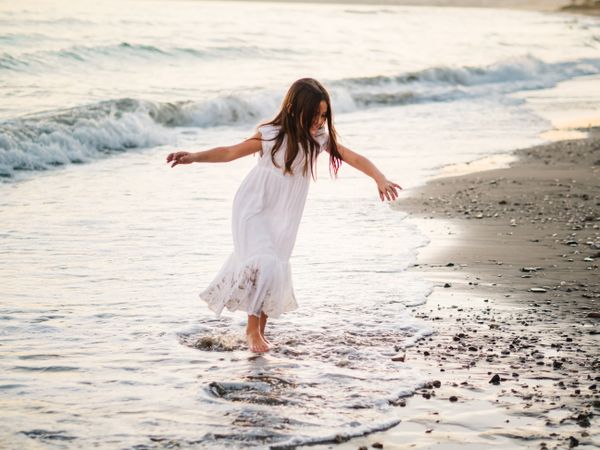 Excited girl running along beach in daylight